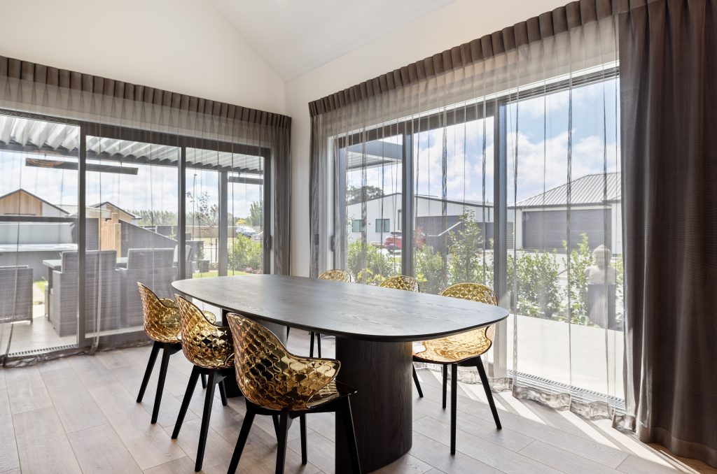 Hallmark Homes Christchurch Oakbridge dining area design and build featuring round dining table, designer lighting, and seamless indoor-outdoor flow with bifold doors