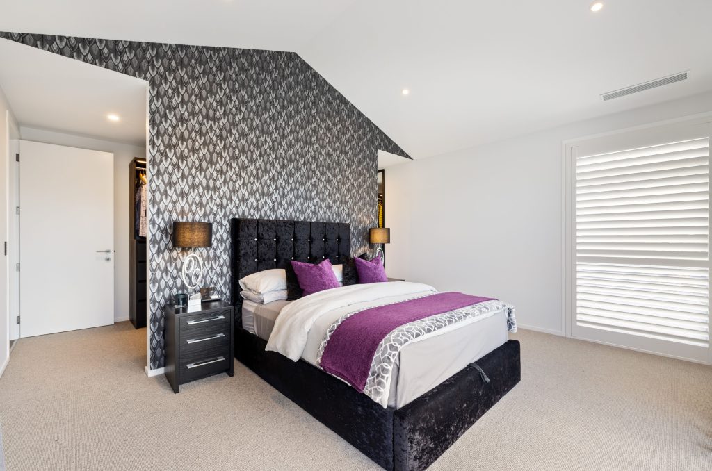 Hallmark Homes Oakbridge master bedroom with geometric wallpaper accent wall and built-in storage - Christchurch prestige home interiors