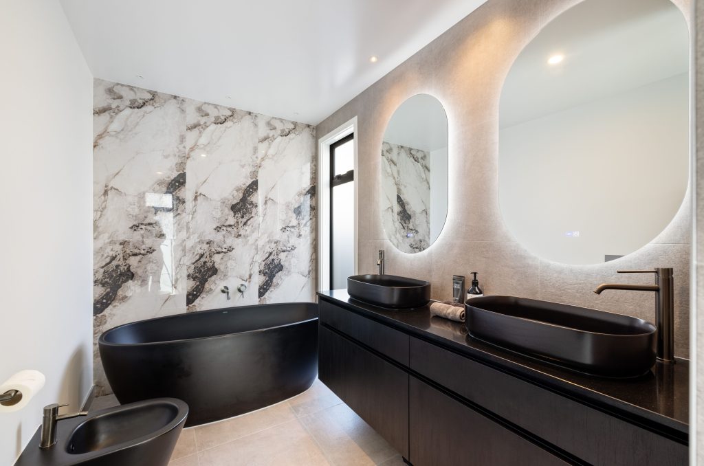 Oakbridge ensuite bathroom design and build by Hallmark Homes Christchurch featuring textured wall panels, marble surfaces, and contemporary black fixtures