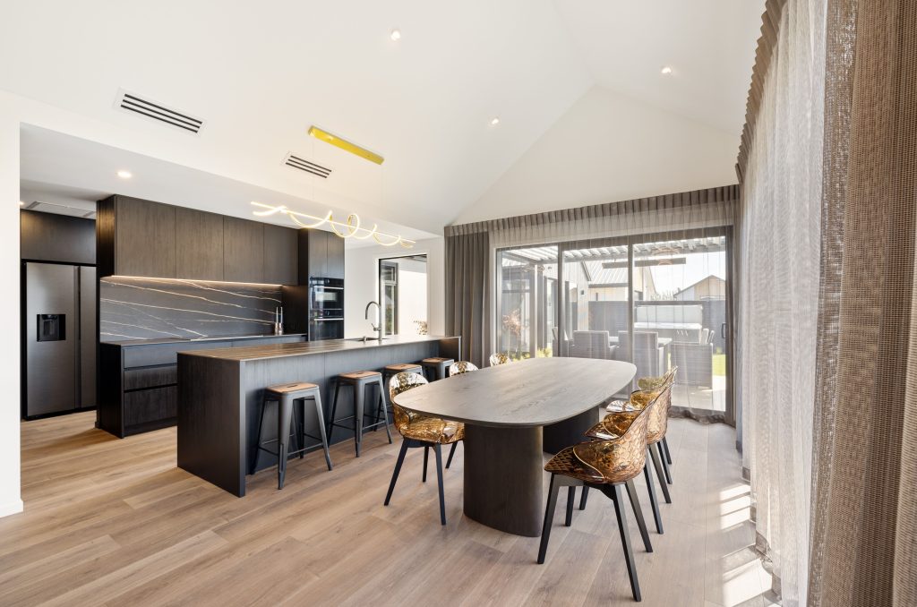 Hallmark Homes Christchurch Oakbridge dining area design and build featuring round dining table, designer lighting, and seamless indoor-outdoor flow with bifold doors