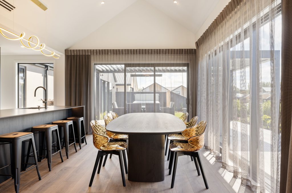 Hallmark Homes Christchurch Oakbridge dining area design and build featuring round dining table, designer lighting, and seamless indoor-outdoor flow with bifold doors