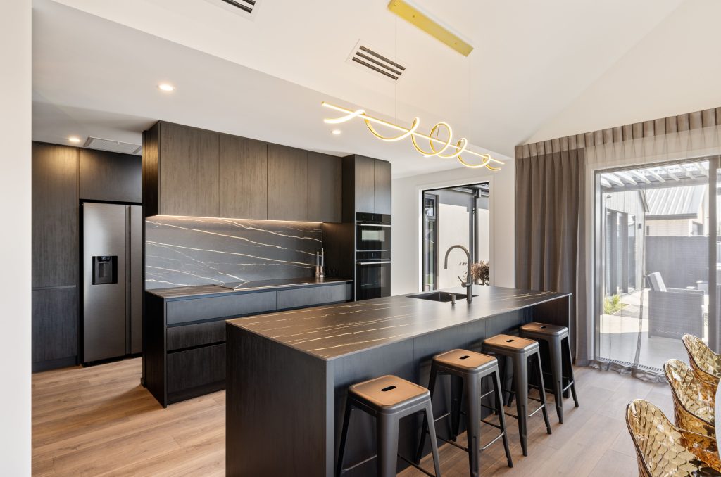 Hallmark Homes Christchurch Oakbridge dining area design and build featuring round dining table, designer lighting, and seamless indoor-outdoor flow with bifold doors